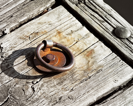Old metal rusty dock ring attached to wooden pierの写真素材