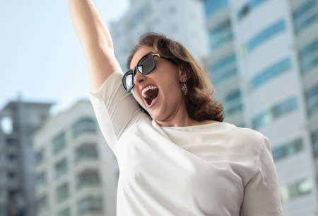 Mid age business woman celebrates deal success in the city.の写真素材