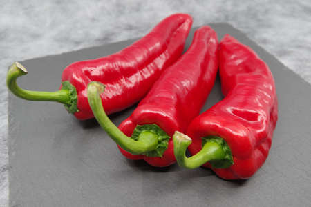 Red sweet peppers on a gray background.