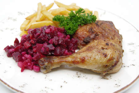Roasted chicken quarter leg with crispy golden brown skin, baked potatoes and beet salad on white plate. Food background.の写真素材