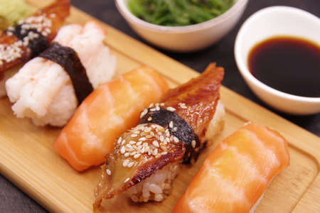 Japanese sushi food on a wooden tray, served with ginger, soy sauce and seaweed salad. Salmon nigiri, shrimp nigiri, unagi nigiriの写真素材