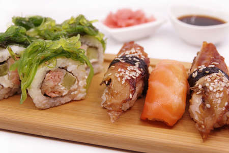 Japanese sushi food on a wooden tray, served with ginger, soy sauce and seaweed salad. Sushi rolls, salmon nigiri, shrimp nigiri, unagi nigiriの写真素材