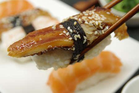 Japanese cuisine: Unagi nigiri, Salmon Nigiri, Shrimp Nigiri. Wooden sushi sticks