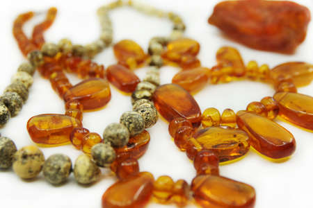 Two necklace made of natural amber and piece of yellow translucent Baltic amber isolated on a white...