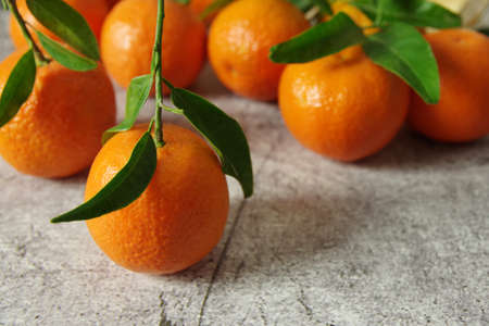 Fresh fragrant mandarins. Ripe juicy tangerines with green leaves on the table.の写真素材