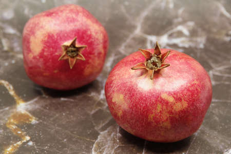 Ripe red pomegranates fruits on a brown background. Seasonal fruits. Royal fruit. Selective focus.の写真素材