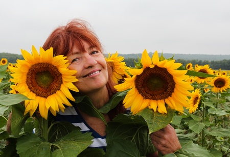 Close-up of a happy, smiling woman surrounded by sunflowers の写真素材