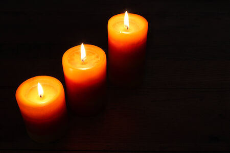 Three burning candles on a dark backgroundの写真素材