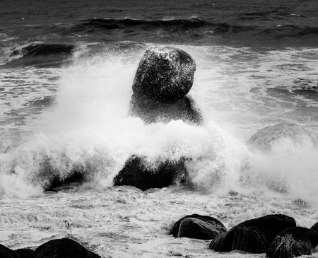 Ocean waves crash in a odd-shaped rock.の写真素材