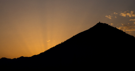 Sunrise below a silhouetted hill.の写真素材