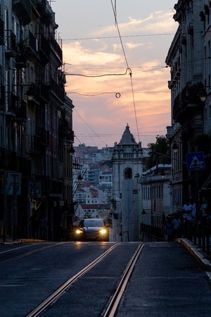 A car approaches in a tight street i n Lisbon just after sunset.のeditorial素材