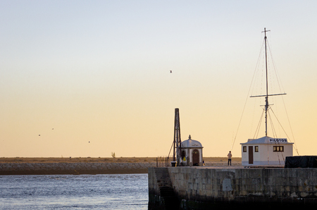 A distant fisherman stands on a pier near a huge cross at dusk.のeditorial素材