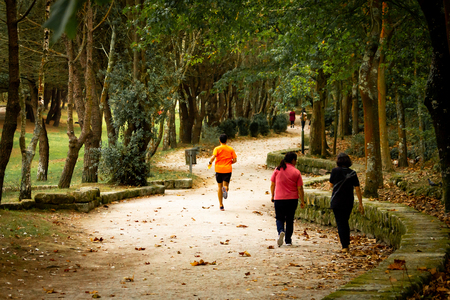 Back view of a male runner passing by two middle-aged women.の写真素材