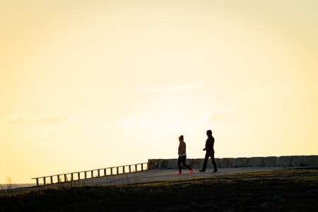 An active couple take a walk after exercising. Side view, warm light.の写真素材