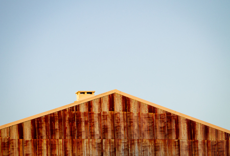 Rusty Building Wall, Roof and Chimney. Copy Space. Clear Day.