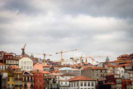 View from Porto cityscape with construction cranes and machines over historic buildings. Cloudy background, copy space.の写真素材