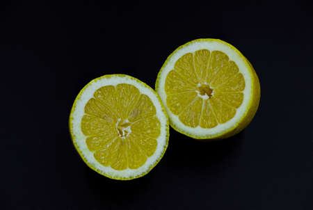 The fruit of a lemon cut in two parts on a black background