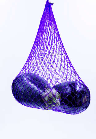 Photograph of two aubergines in a purple mesh bagの写真素材