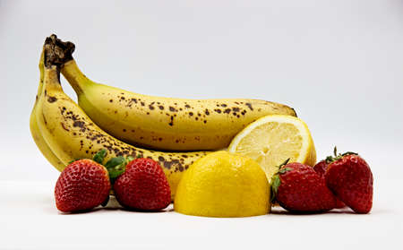 Fresh fruit salad with bananas, strawberries and lemon on a light backgroundの写真素材