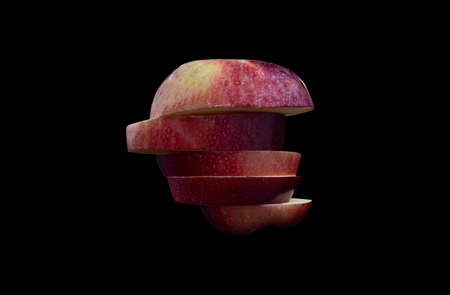 A red apple cut into slice on a dark backgroundの写真素材