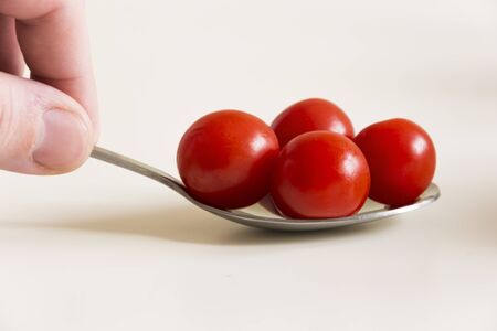Little red tomatoes on a spoonの写真素材