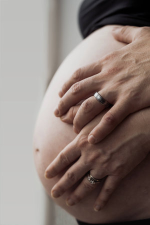 Pregnant woman with her husband hands around her belly.Happy pregnant couple hugging. Man and woman...