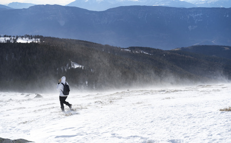 Women hiking with a backpackt hrough a snowstorm on  the top of a mountain in south tyrol italyの写真素材