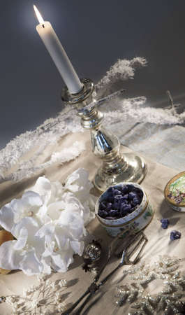 Violet blossom leaves candied in sugar and silver candleholder on a traditionally decorated table during christmastimeの写真素材