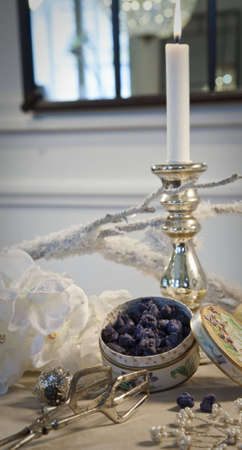 Violet blossom leaves candied in sugar and silver candleholder on a traditionally decorated table during christmastime, with mirror in the background.の写真素材