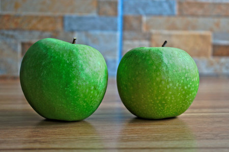 Two green apples on a wooden tableの写真素材