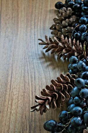 Grapes and pine cones on a wooden tableの写真素材