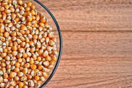Popcorn kernels in a bowl on a wooden tableの写真素材