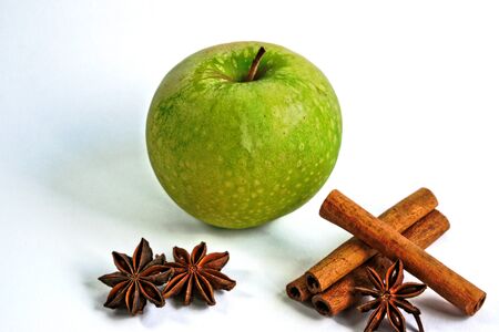 Green apple with cinnamon sticks and star anise on a white backgroundの写真素材