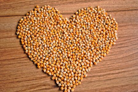 Popcorn kernels in a heart shape on a wooden tableの写真素材