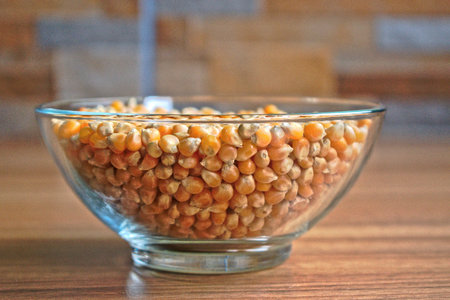 Popcorn kernels in a bowl on a wooden tableの写真素材