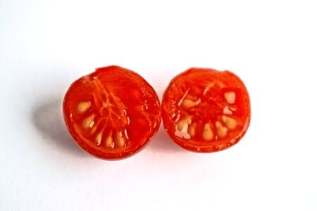 Closeup of two cherry tomato halves on a white background