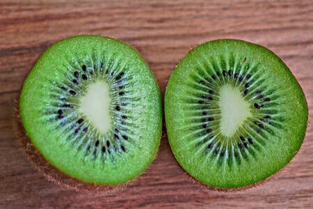 Closeup of two kiwi halves on a wooden tableの写真素材