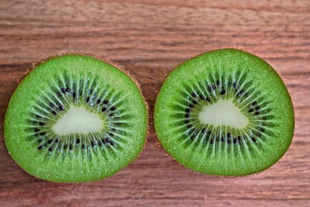 Closeup of two kiwi halves on a wooden tableの写真素材