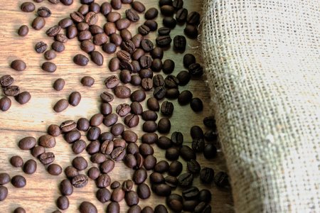 Coffee beans and a burlap sack on a wooden tableの写真素材