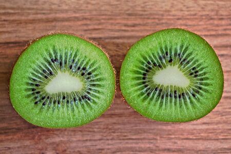 Closeup of two kiwi halves on a wooden tableの写真素材