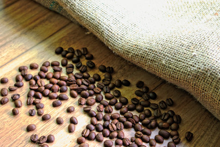 Coffee beans and a burlap sack on a wooden tableの写真素材