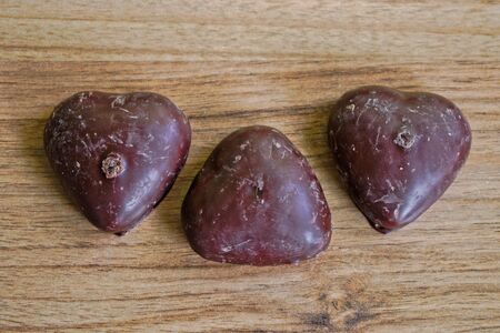 Chocolate covered gingerbread hearts on a wooden tableの写真素材