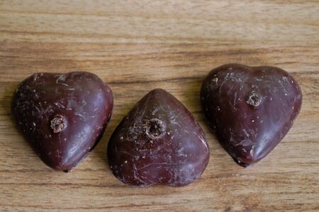 Chocolate covered gingerbread hearts on a wooden tableの写真素材