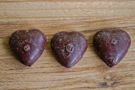 Chocolate covered gingerbread hearts on a wooden tableの写真素材