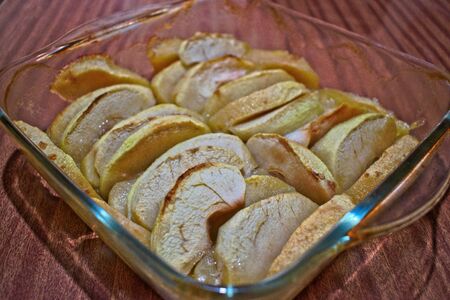 Baked apples in a clear dish on a wooden tableの写真素材