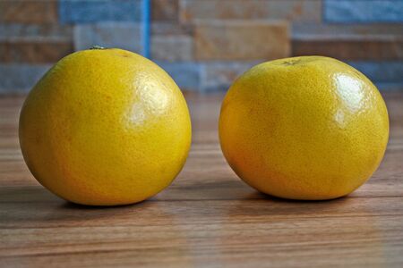 Two yellow grapefruits on a wooden tableの写真素材