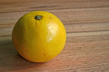 Closeup of a yellow grapefruit on a wooden tableの写真素材