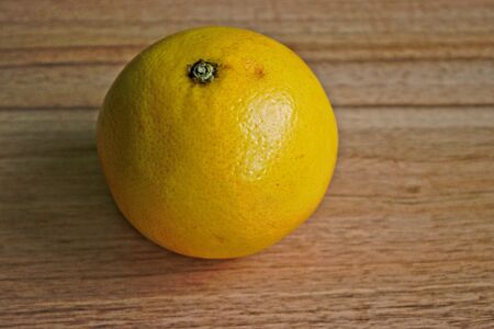 Closeup of a yellow grapefruit on a wooden tableの写真素材