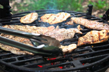 Grilling chicken fillets at a barbecueの写真素材
