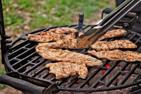 Grilling chicken fillets at a barbecueの写真素材